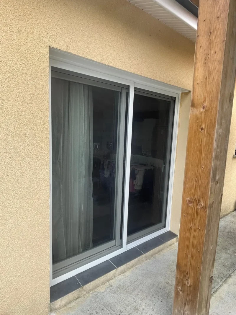 Baie vitrée coulissante blanche sur façade beige