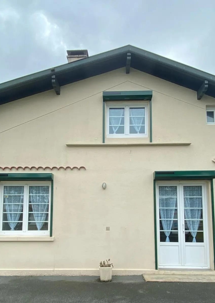 Façade de maison beige aux volets verts
