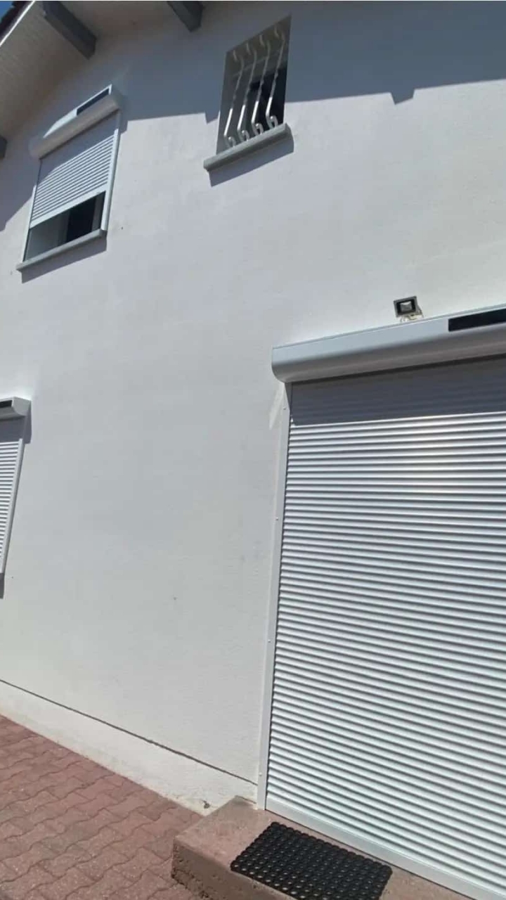 Façade maison blanche avec volets roulants fermés