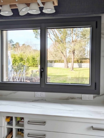 Fenêtre aluminium anthracite sur mesure dans une cuisine, plan de travail marbre