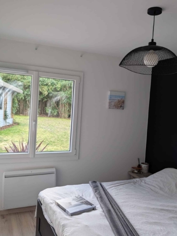 Fenêtre PVC blanche sur mesure dans une chambre, vue sur jardin
