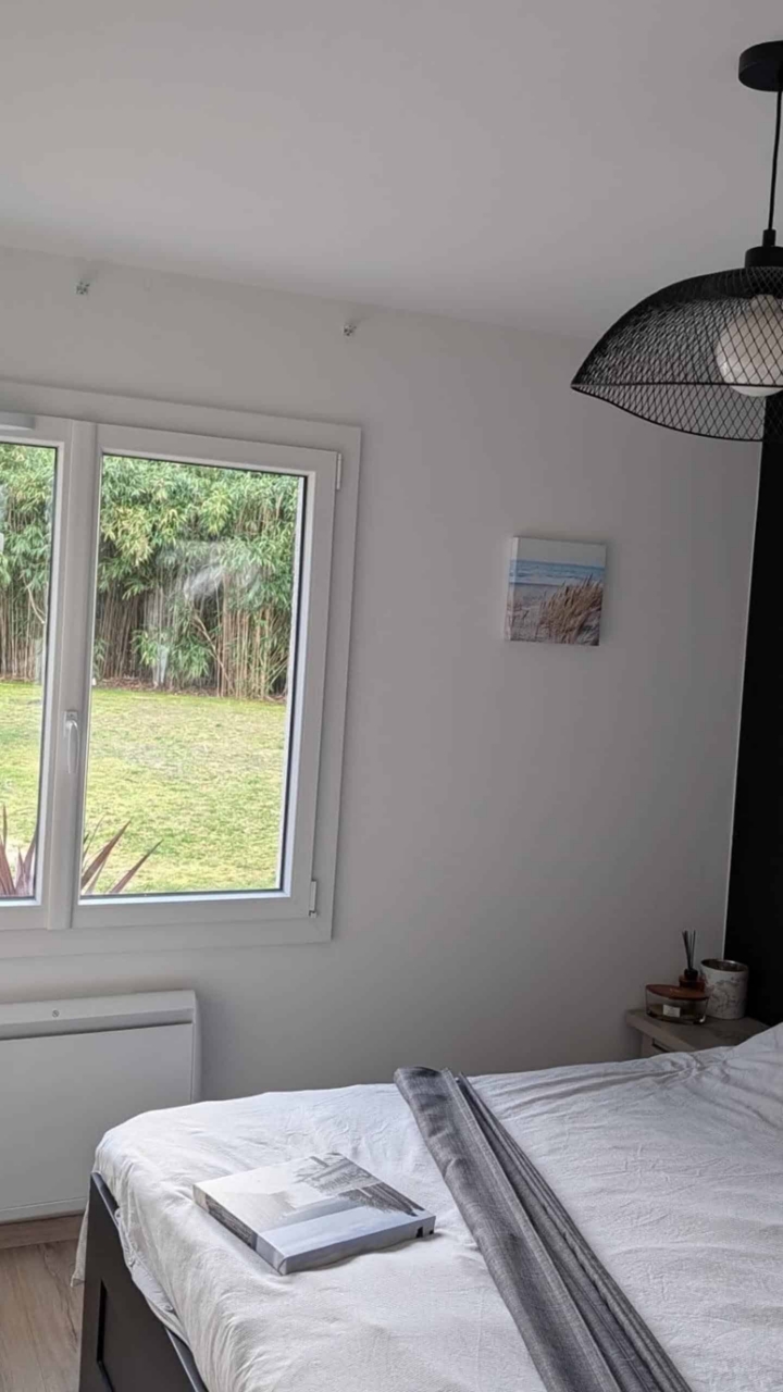 Fenêtre PVC blanche sur mesure dans une chambre, vue sur jardin