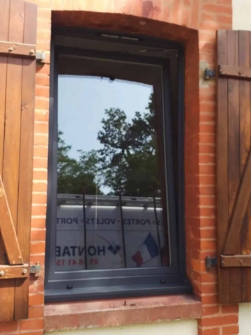 Fenêtre aluminium anthracite posée en rénovation, encadrement brique et volets bois