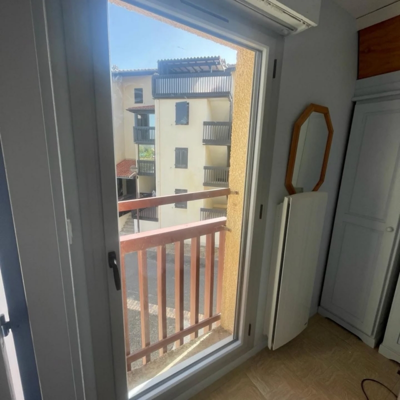 Porte-fenêtre en aluminium gris dans une chambre à Vieux-Boucau, ouverte sur le balcon