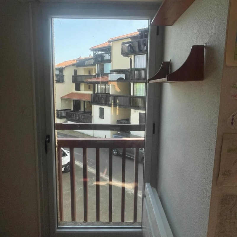 Porte-fenêtre en aluminium gris dans une chambre à Vieux-Boucau, ouverte sur le balcon