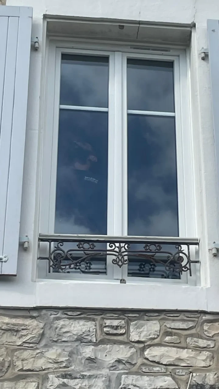 Fenêtre blanche avec volets bleus et balcon en fer