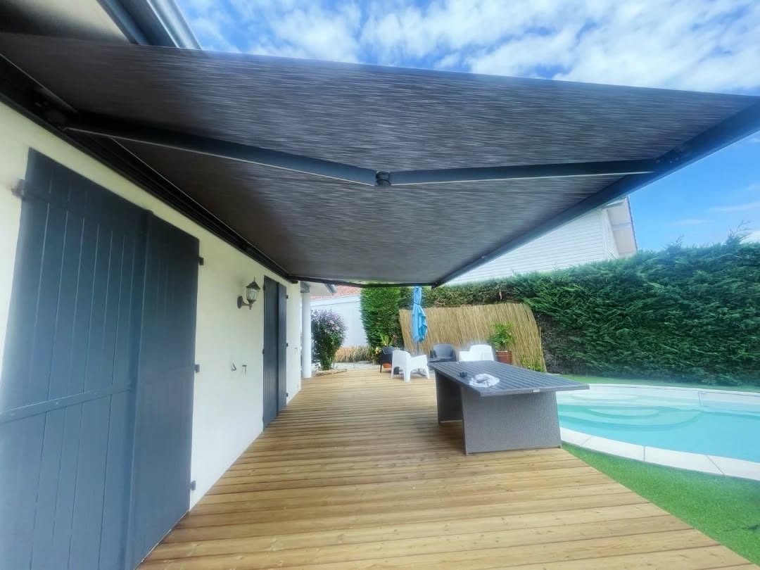 Store banne coffre déployé au-dessus de la terrasse en bois et de la piscine, à Soustons