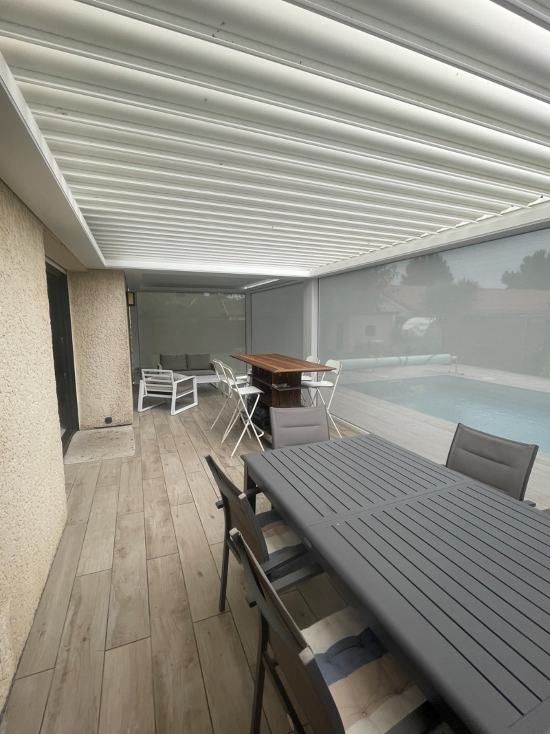 Bandeau LED intégré dans la poutre d'une pergola bioclimatique au-dessus d'une table de terrasse