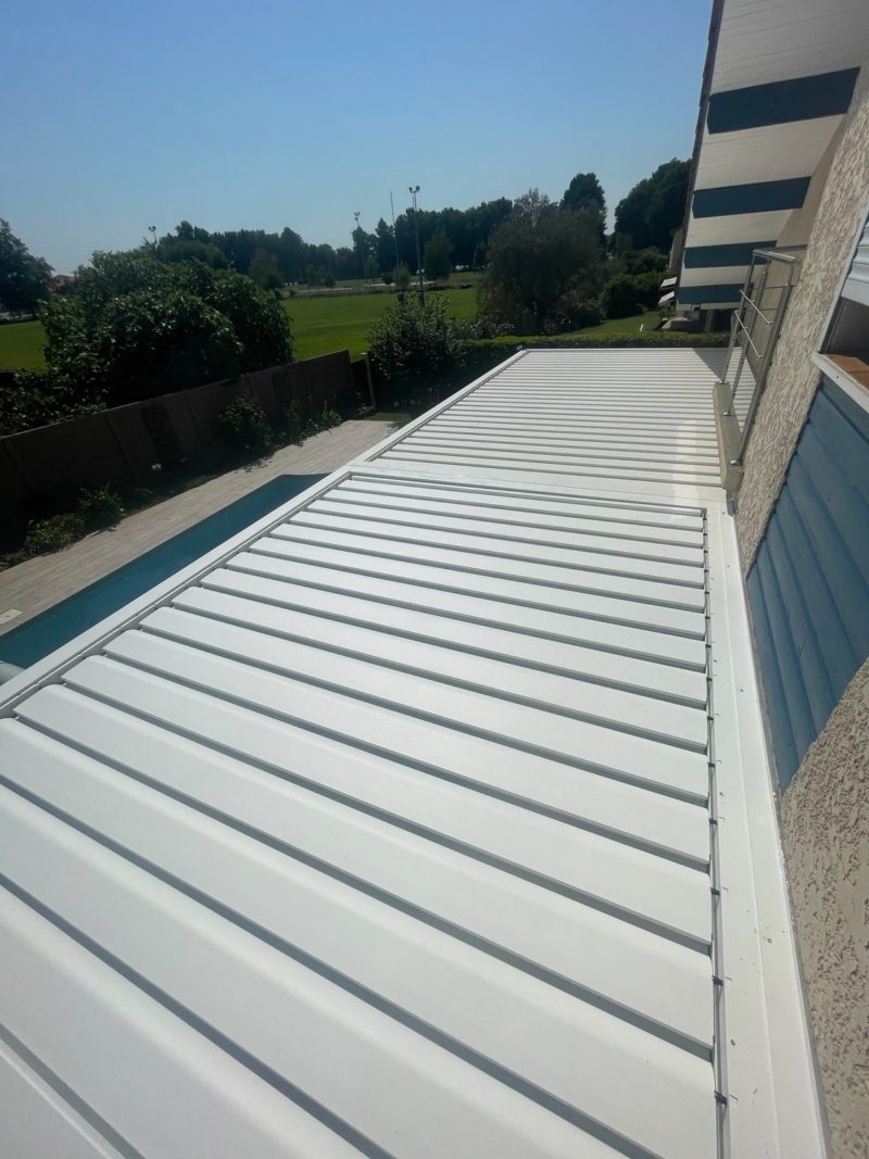 Vue de dessus des lames orientables des deux modules de pergola bioclimatique, alignées dans le prolongement l'une de l'autre