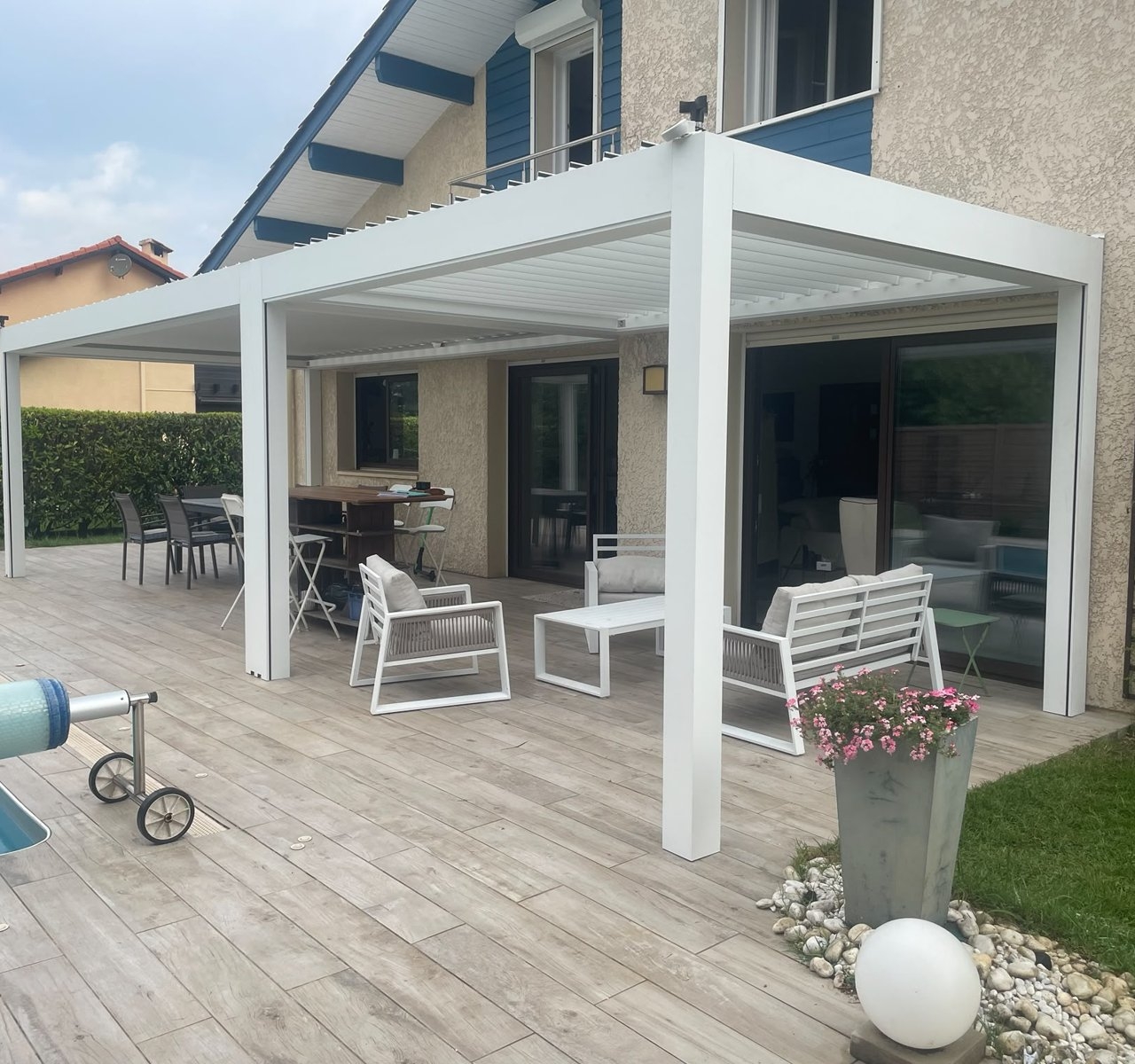 Terrasse couverte par une pergola bioclimatique en aluminium blanc, salon de jardin et coin repas, maison dans les Landes