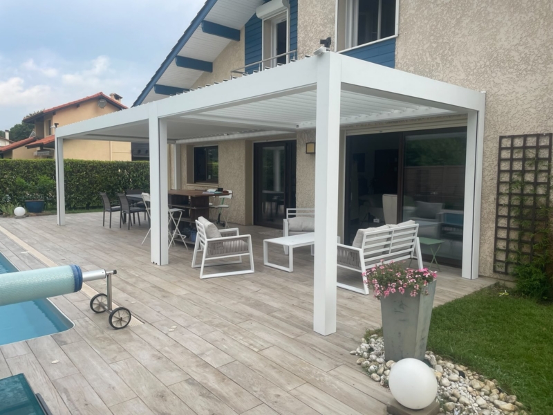 Terrasse couverte par une pergola bioclimatique en aluminium blanc, salon de jardin et coin repas, maison dans les Landes