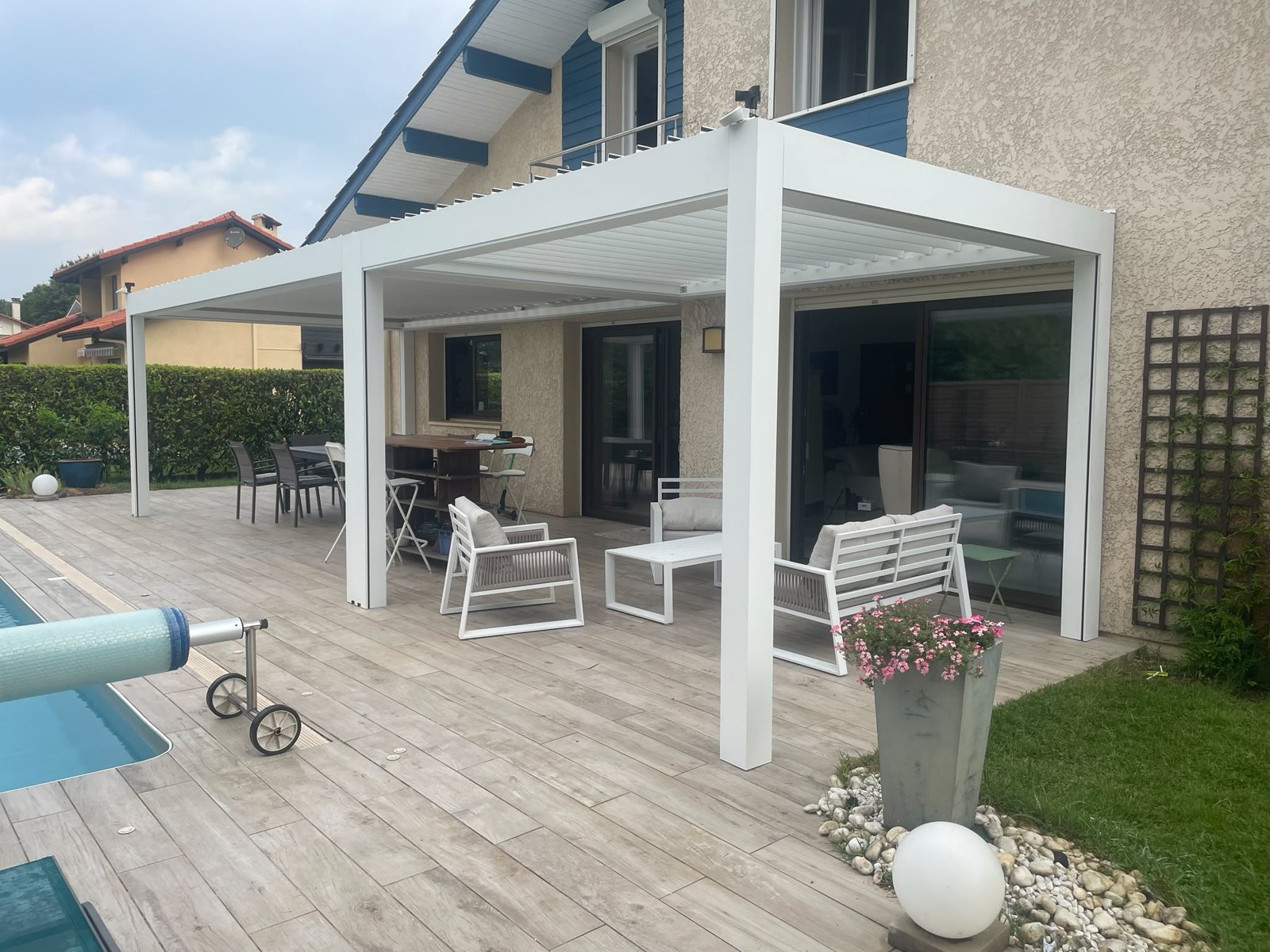 Terrasse couverte par une pergola bioclimatique en aluminium blanc, salon de jardin et coin repas, maison dans les Landes