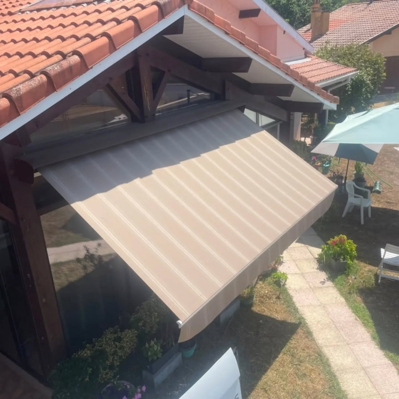Vue de dessus de la toile neuve d'un store banne rénové par Hontabal, au-dessus d'une baie vitrée à Castets