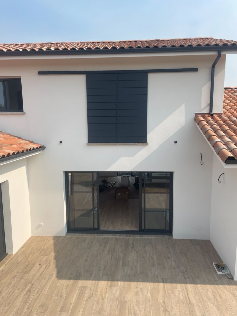 Façade arrière d'une maison contemporaine à Mimizan avec volet coulissant aluminium à l'étage, au-dessus de la terrasse et de la baie vitrée