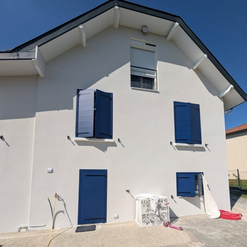 Volet roulant à motorisation solaire Somfy à l'étage, au-dessus des volets battants bleus, maison du sud des Landes