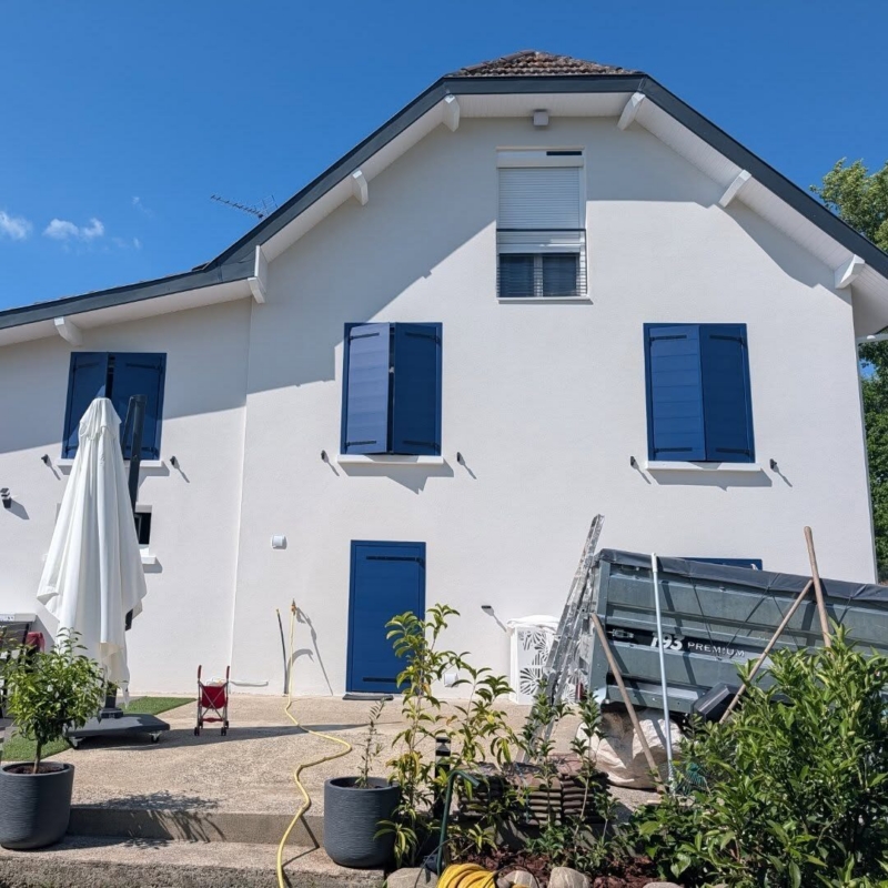 Façade arrière après rénovation : volets battants aluminium Cécilia bleus sur les fenêtres PVC, volet roulant à l'étage