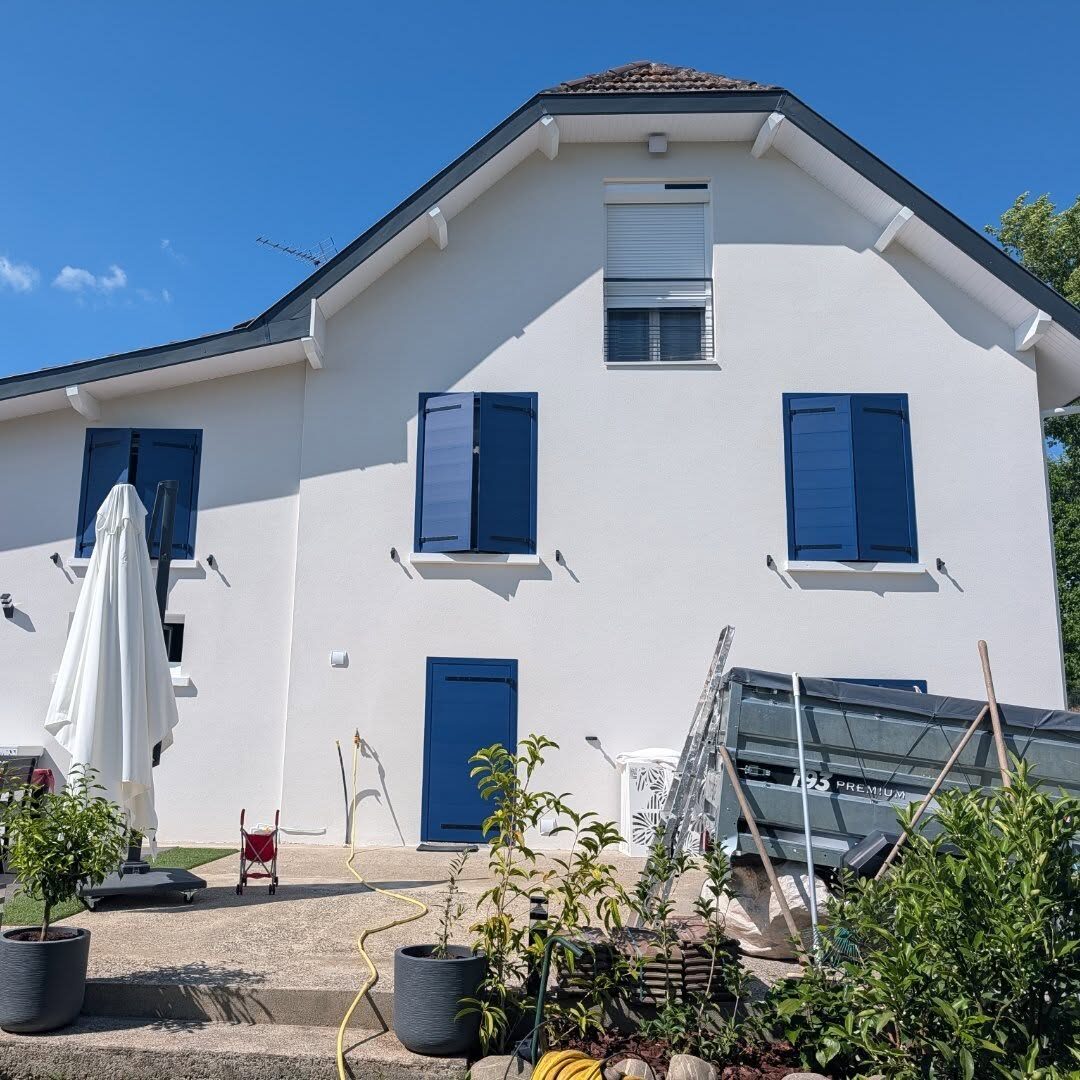 Façade arrière après rénovation : volets battants aluminium Cécilia bleus sur les fenêtres PVC, volet roulant à l'étage