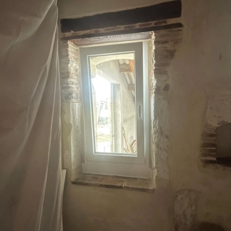 Fenêtre PVC dans une ouverture en briques, tablette en terre cuite et linteau en bois, bâti ancien à Misson