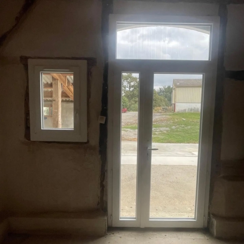 Porte-fenêtre à imposte et petite fenêtre PVC blanches dans un mur en torchis à Misson