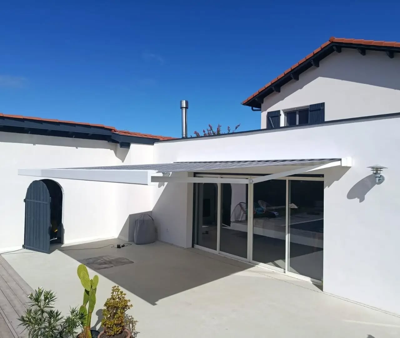 Store banne blanc de 5 m sur 4 m d'avancée déployé au-dessus de la terrasse d'une maison à Soustons