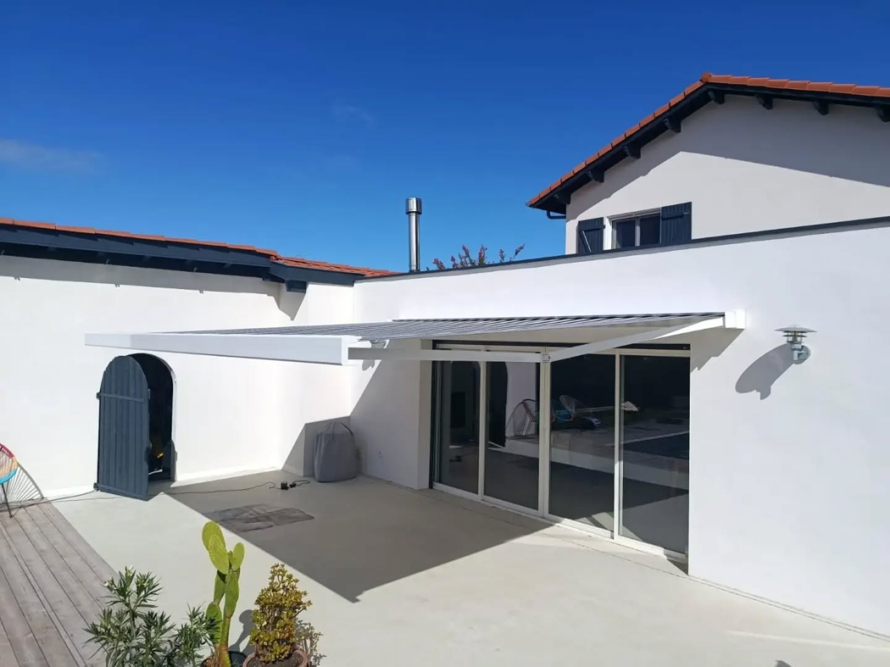 Store banne blanc de 5 m sur 4 m d'avancée déployé au-dessus de la terrasse d'une maison à Soustons