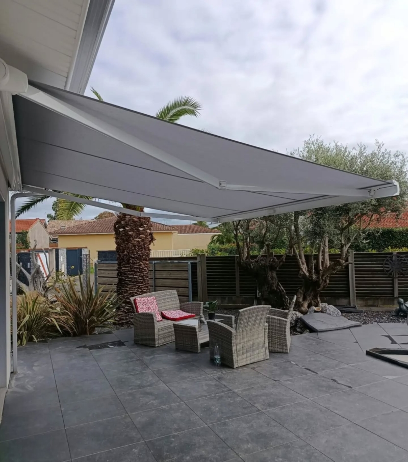 Store coffre motorisé Somfy déployé avec sa toile grise au-dessus d'une terrasse carrelée à Soustons