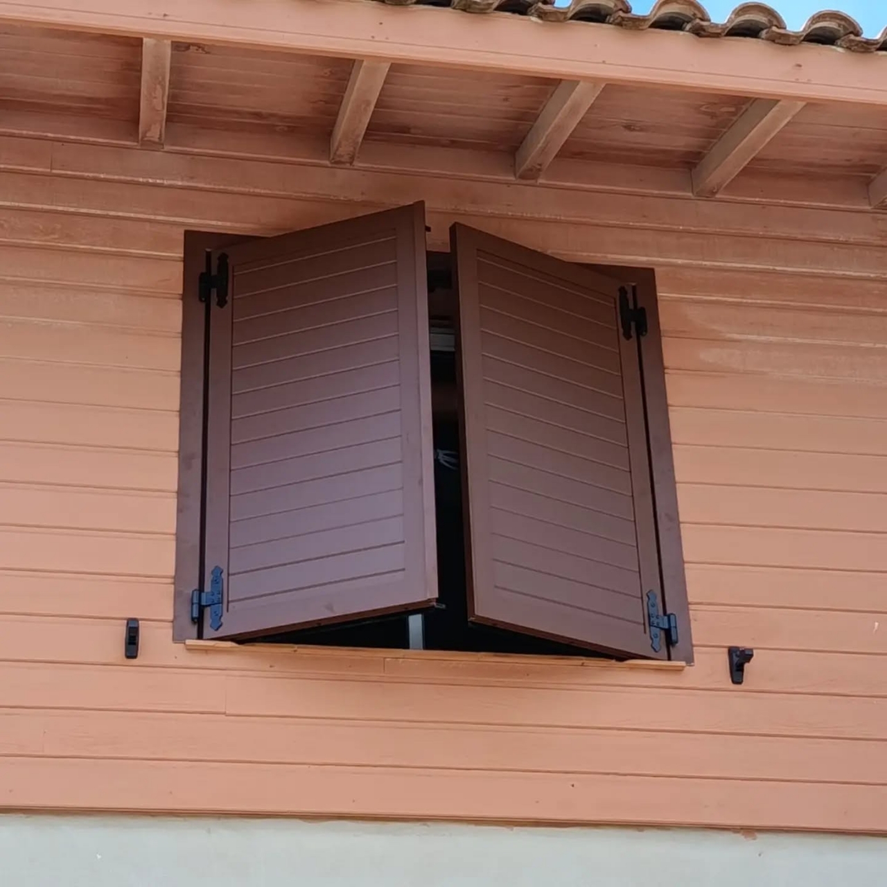 Volets battants aluminium bruns à lames horizontales posés sur une façade à bardage bois à Vieux-Boucau