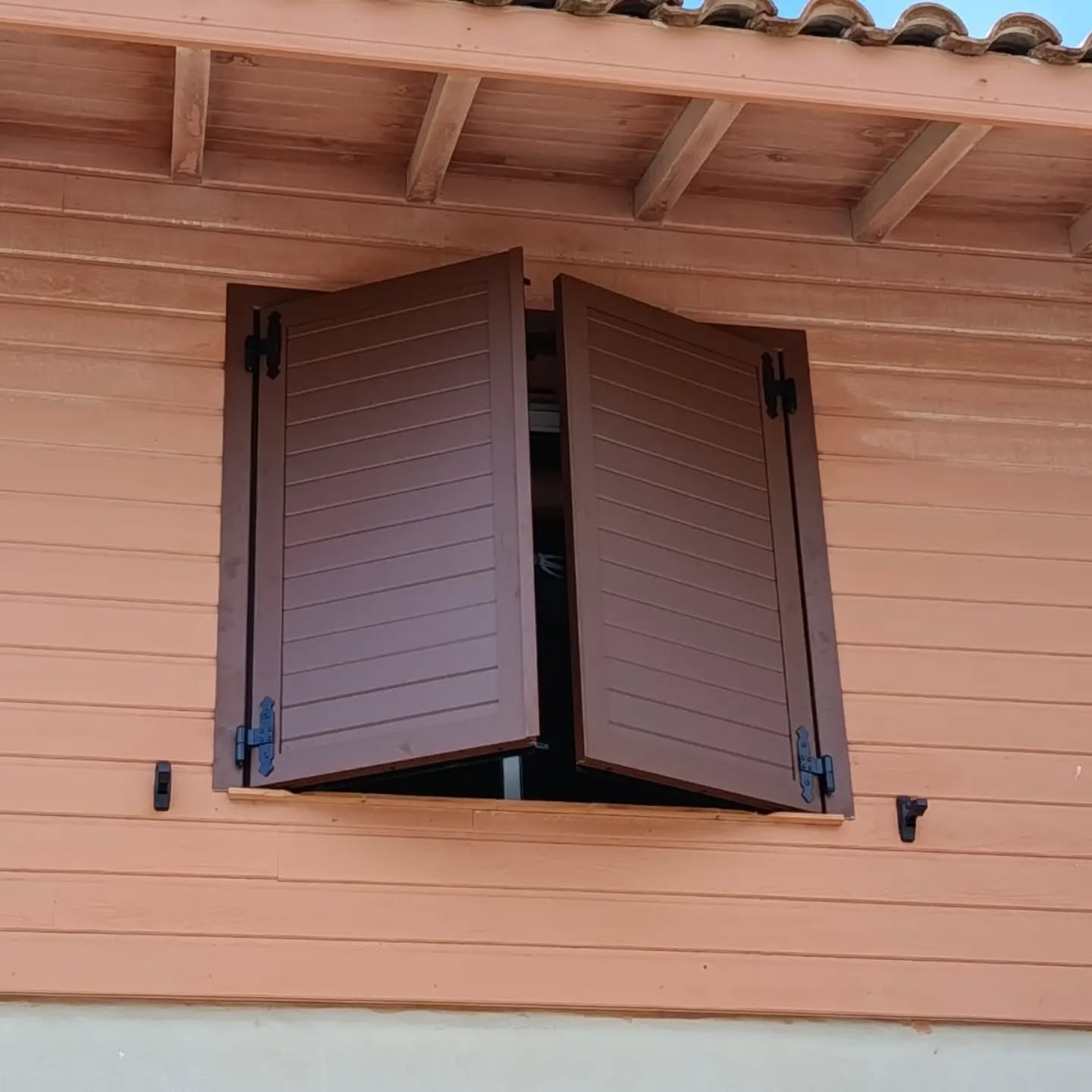 Volets battants aluminium bruns à lames horizontales posés sur une façade à bardage bois à Vieux-Boucau